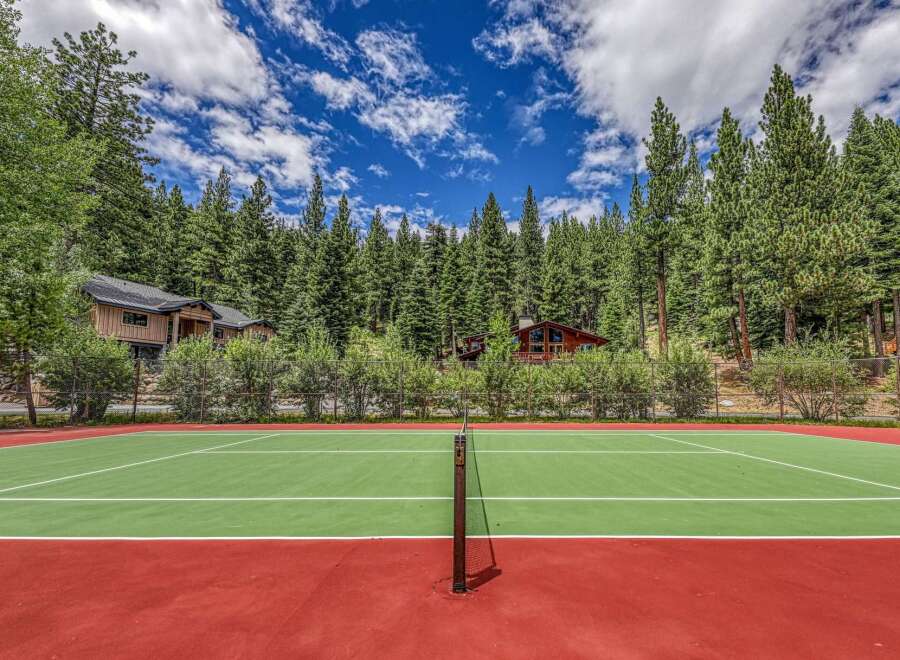 Enjoy outdoor recreation with this private tennis court, nestled amidst a lush forest setting.