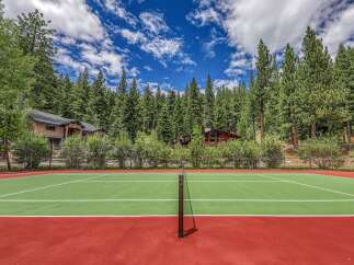 Enjoy outdoor recreation with this private tennis court, nestled amidst a lush forest setting.