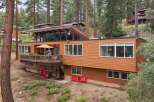 Nestled among tall pine trees, this multi-level home offers a unique architectural design with expansive windows and a warm, wood-paneled exterior.