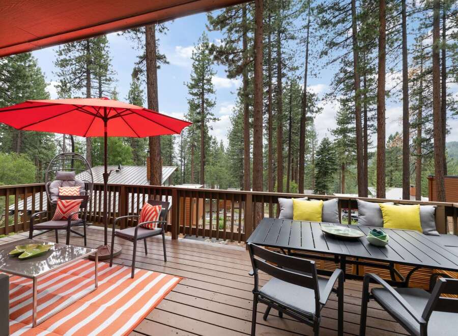 Enjoy the serene mountain lifestyle on this spacious deck, perfect for entertaining or relaxing amidst towering pine trees.