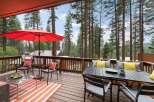 Enjoy the serene mountain lifestyle on this spacious deck, perfect for entertaining or relaxing amidst towering pine trees.