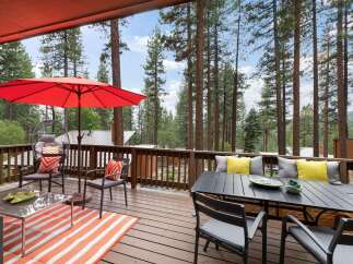 Enjoy the serene mountain lifestyle on this spacious deck, perfect for entertaining or relaxing amidst towering pine trees.