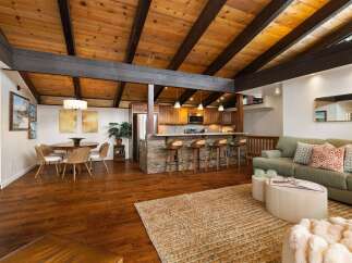 Experience open-concept living with a stunning vaulted wood-beamed ceiling and a modern kitchen island perfect for entertaining.