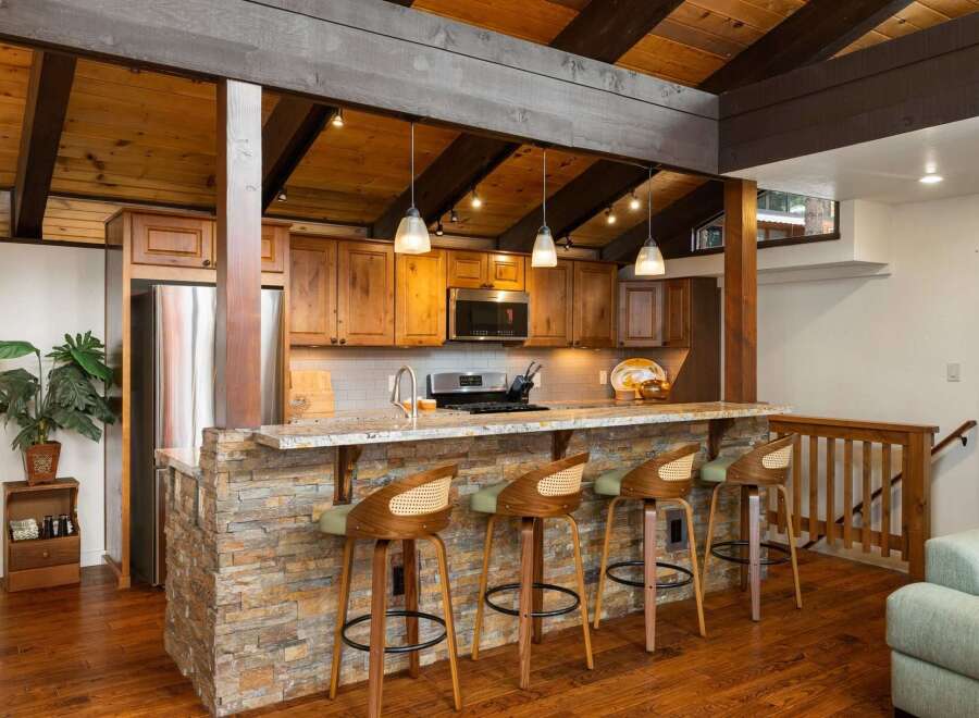 Experience rustic charm in this kitchen featuring a stone-accented island with granite countertops, perfect for casual dining and entertaining.