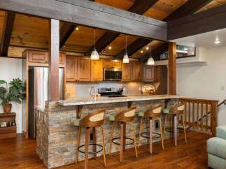 Experience rustic charm in this kitchen featuring a stone-accented island with granite countertops, perfect for casual dining and entertaining.