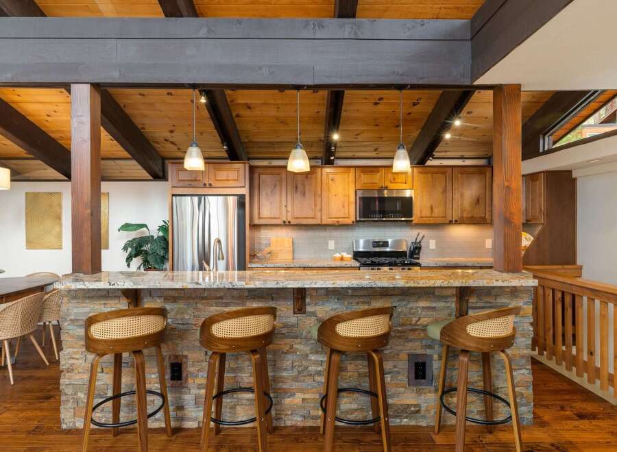 Experience rustic charm in this stunning kitchen featuring a stone-clad island bar with comfortable seating, perfect for casual dining and entertaining.