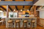 Experience rustic charm in this stunning kitchen featuring a stone-clad island bar with comfortable seating, perfect for casual dining and entertaining.