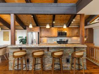 Experience rustic charm in this stunning kitchen featuring a stone-clad island bar with comfortable seating, perfect for casual dining and entertaining.