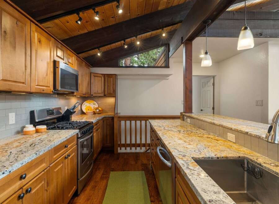 This stunning kitchen boasts beautiful natural wood cabinetry and a striking granite countertop that extends into a breakfast bar.