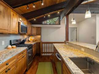This stunning kitchen boasts beautiful natural wood cabinetry and a striking granite countertop that extends into a breakfast bar.