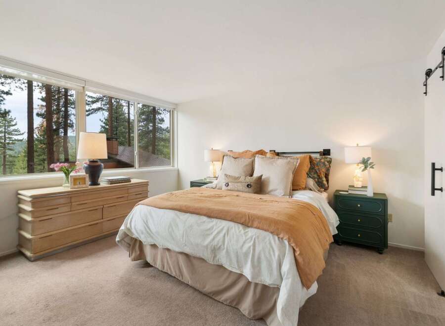 Experience serene living in this charming bedroom, featuring a large dresser and a comfortable bed adorned with plush pillows and a cozy rust-colored throw.