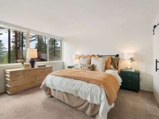 Experience serene living in this charming bedroom, featuring a large dresser and a comfortable bed adorned with plush pillows and a cozy rust-colored throw.