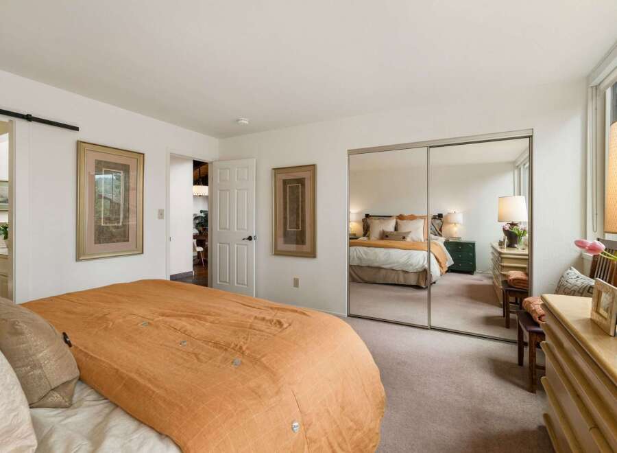 This inviting bedroom features a large bed with a warm orange comforter, perfect for cozy nights.