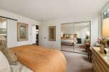 This inviting bedroom features a large bed with a warm orange comforter, perfect for cozy nights.