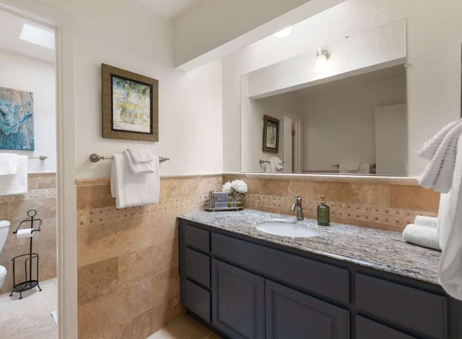 This charming bathroom features a spacious vanity with a granite countertop and a large mirror, perfect for your morning routine.