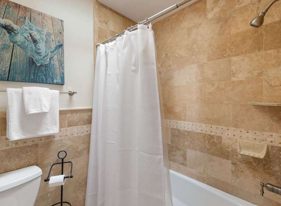 This bathroom features a luxurious travertine tile shower and tub surround, creating a spa-like atmosphere.