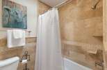 This bathroom features a luxurious travertine tile shower and tub surround, creating a spa-like atmosphere.