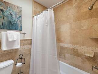 This bathroom features a luxurious travertine tile shower and tub surround, creating a spa-like atmosphere.