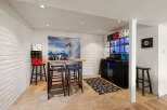 This basement bar area features a unique ski-themed mural and a modern bar with a built-in cooler.