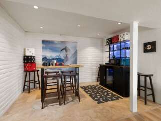 This basement bar area features a unique ski-themed mural and a modern bar with a built-in cooler.