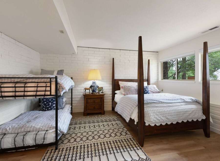 This charming bedroom offers versatile sleeping arrangements with a classic wooden four-poster bed and a sturdy metal bunk bed, perfect for families or guests.