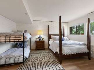 This charming bedroom offers versatile sleeping arrangements with a classic wooden four-poster bed and a sturdy metal bunk bed, perfect for families or guests.