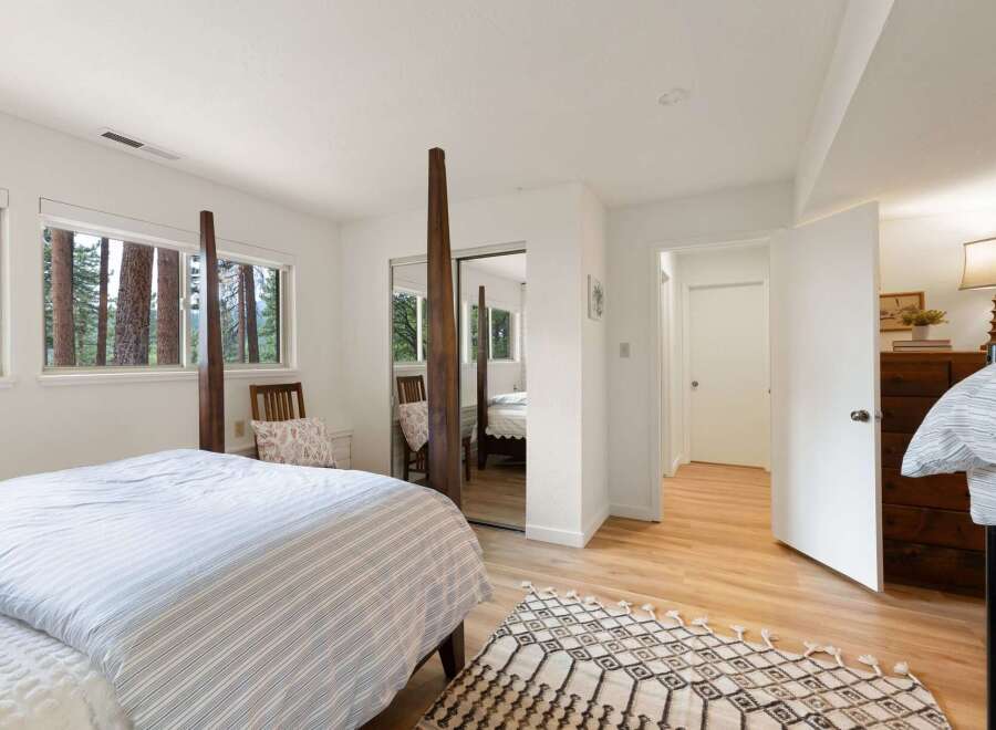 Experience serene living in this charming bedroom, featuring large windows that frame picturesque forest views.