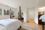 Experience serene living in this charming bedroom, featuring large windows that frame picturesque forest views.