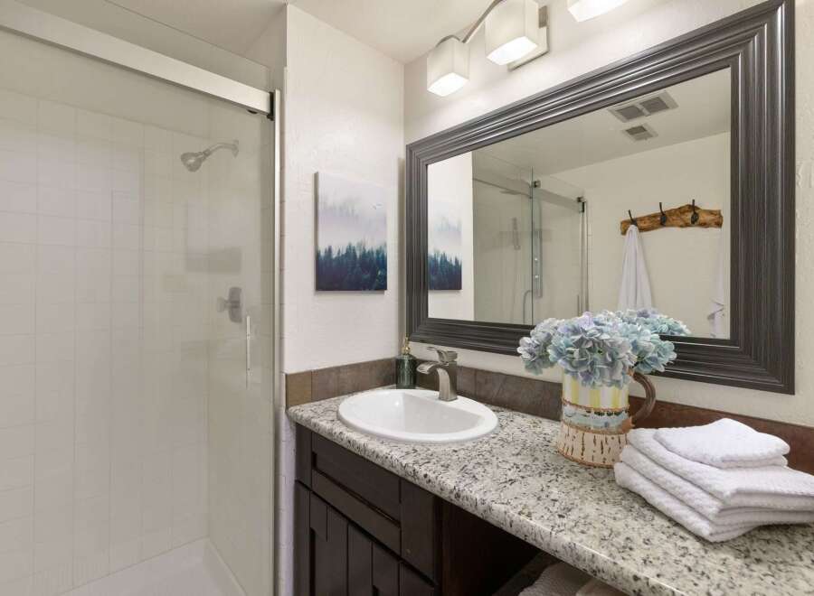 This modern bathroom features a sleek glass-enclosed shower with white tiled walls, perfect for a refreshing start to your day.