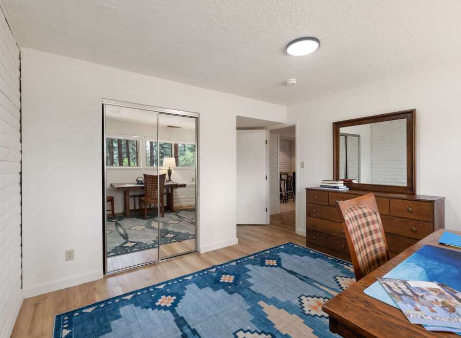 This bedroom offers a versatile space with a mirrored closet and a built-in desk area, perfect for a home office or study nook.