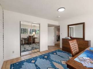 This bedroom offers a versatile space with a mirrored closet and a built-in desk area, perfect for a home office or study nook.