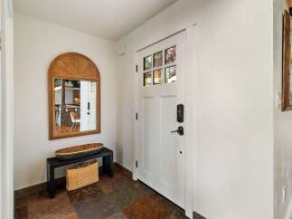 Step into this welcoming entryway featuring a stylish arched mirror and a convenient bench with storage.