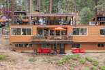 Nestled among tall pine trees, this multi-level home offers a unique architectural design with warm wood siding and expansive windows.