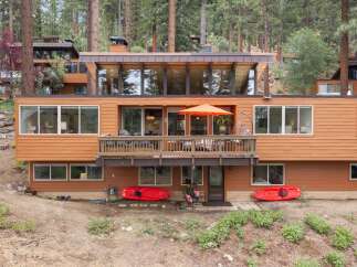 Nestled among tall pine trees, this multi-level home offers a unique architectural design with warm wood siding and expansive windows.