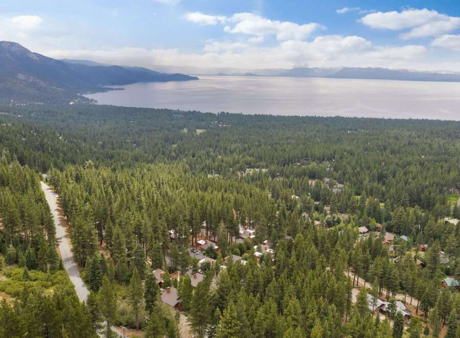 Nestled amidst a dense forest of towering pine trees, this property offers a serene escape with stunning views of a vast, tranquil lake and distant mountains.