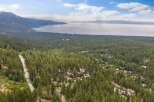 Nestled amidst a dense forest of towering pine trees, this property offers a serene escape with stunning views of a vast, tranquil lake and distant mountains.