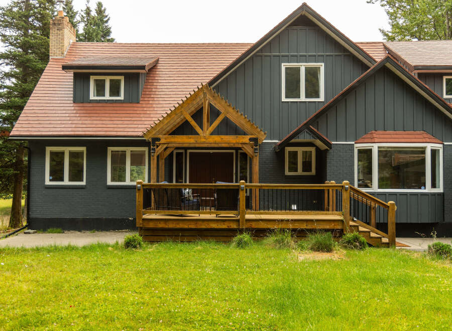 Discover this charming home featuring a rustic wooden porch and a welcoming deck, perfect for outdoor relaxation.