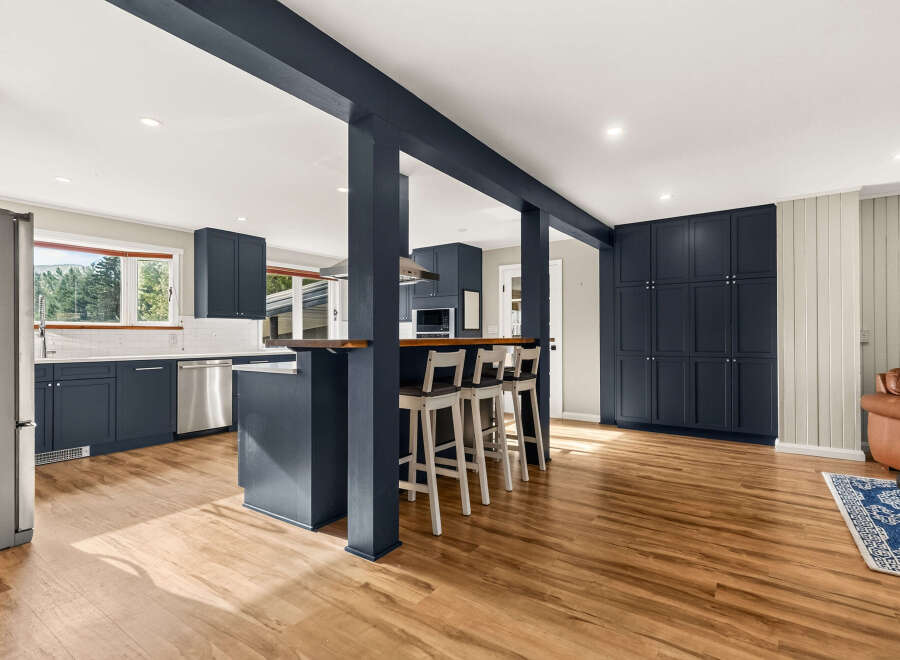 Discover this beautifully renovated kitchen featuring sleek navy cabinetry and a spacious island with bar seating, perfect for entertaining.