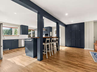 Discover this beautifully renovated kitchen featuring sleek navy cabinetry and a spacious island with bar seating, perfect for entertaining.