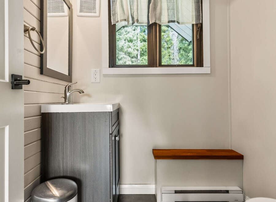 This charming bathroom features a modern vanity with a sleek faucet, complemented by a stylish trash can.