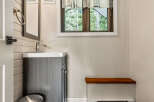This charming bathroom features a modern vanity with a sleek faucet, complemented by a stylish trash can.