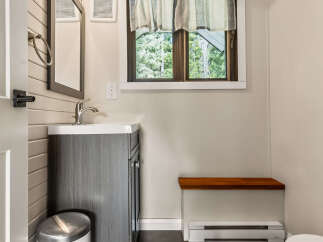 This charming bathroom features a modern vanity with a sleek faucet, complemented by a stylish trash can.