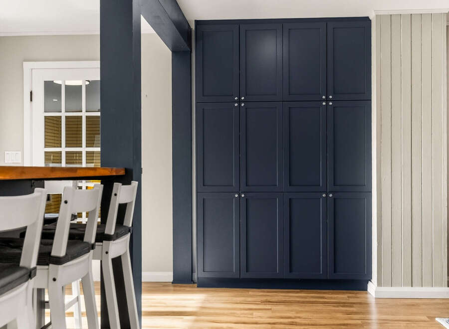 Discover this beautifully renovated kitchen featuring a sleek navy blue cabinet wall and a warm, inviting breakfast bar.