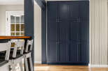 Discover this beautifully renovated kitchen featuring a sleek navy blue cabinet wall and a warm, inviting breakfast bar.