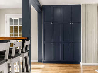 Discover this beautifully renovated kitchen featuring a sleek navy blue cabinet wall and a warm, inviting breakfast bar.