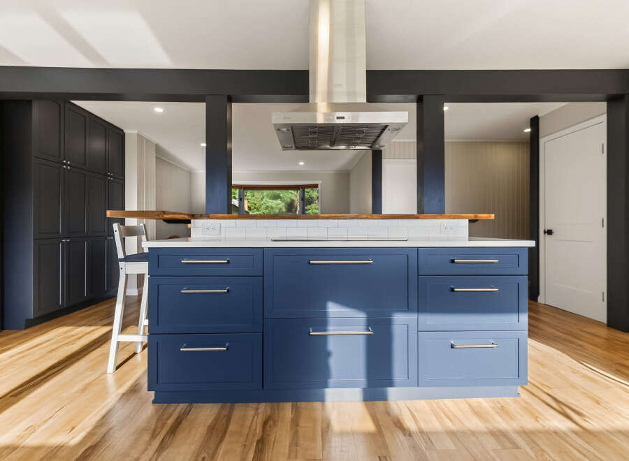 Experience modern living in this stunning kitchen featuring a bold blue island with sleek hardware and a white tiled backsplash.