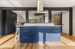 Experience modern living in this stunning kitchen featuring a bold blue island with sleek hardware and a white tiled backsplash.