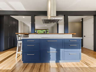 Experience modern living in this stunning kitchen featuring a bold blue island with sleek hardware and a white tiled backsplash.