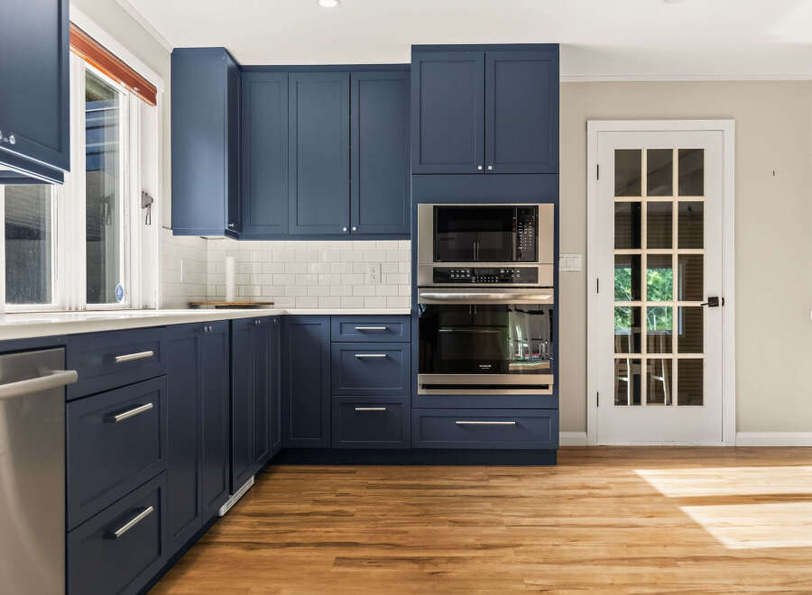 Experience modern elegance in this stunning kitchen, featuring deep navy blue cabinetry that provides a sophisticated contrast to the crisp white subway tile backsplash.