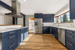 Experience modern living in this stunning kitchen featuring sleek navy blue cabinetry and pristine white countertops.